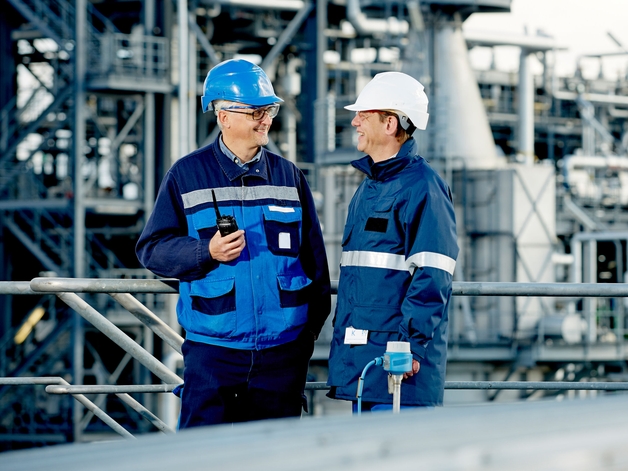 Zwei Ingenieure arbeiten stehend in einer Raffinerie.