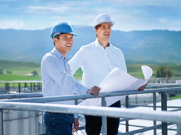 Two engineers standing on top of a storage tank.