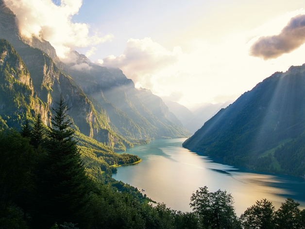 Der See ist umgeben von bewaldeten Bergen.